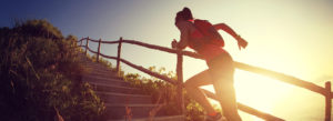 Sportlerin rennt draußen eine Treppe im Sonnenlicht hoch